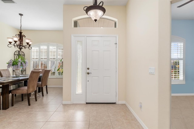 foyer featuring light tile patterned flooring, a healthy amount of sunlight, and a notable chandelier