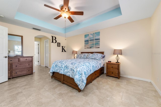 bedroom with ceiling fan and a raised ceiling