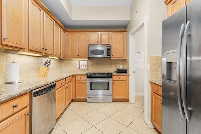 kitchen with light stone countertops, appliances with stainless steel finishes, and decorative backsplash