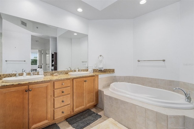 bathroom with vanity, tile patterned flooring, and tiled tub