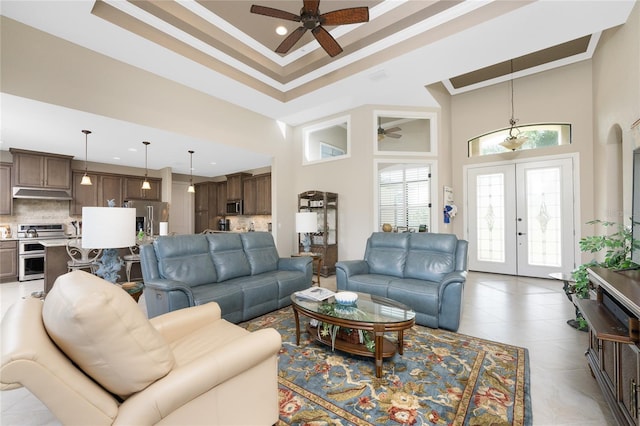 living room with a high ceiling, french doors, crown molding, light tile patterned floors, and ceiling fan