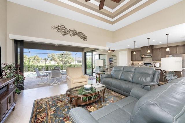 living room featuring ornamental molding, light tile patterned floors, a high ceiling, and ceiling fan