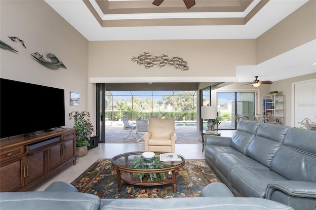 living room with ceiling fan, light tile patterned floors, and a high ceiling