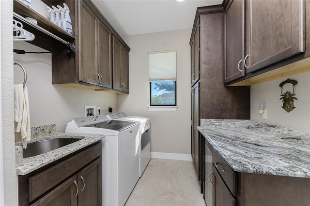 clothes washing area featuring sink, cabinets, and washing machine and clothes dryer