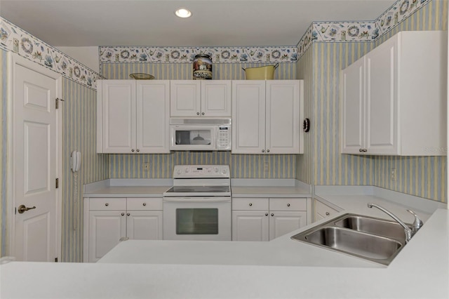 kitchen featuring white appliances, white cabinetry, and sink