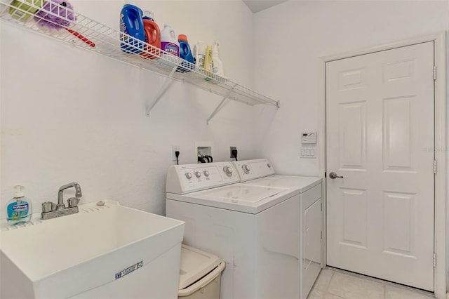 washroom featuring sink, washer and clothes dryer, and light tile patterned flooring