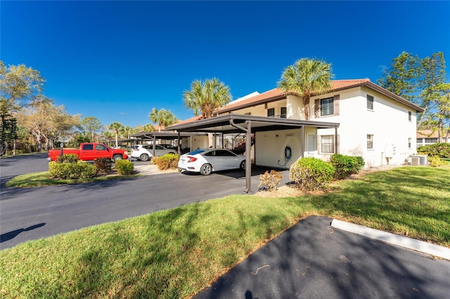 404 Pine Hollow Cir Unit 404, Englewood, FL 34223 - view of front of property featuring stucco siding, a front lawn, covered parking, and central air condition unit