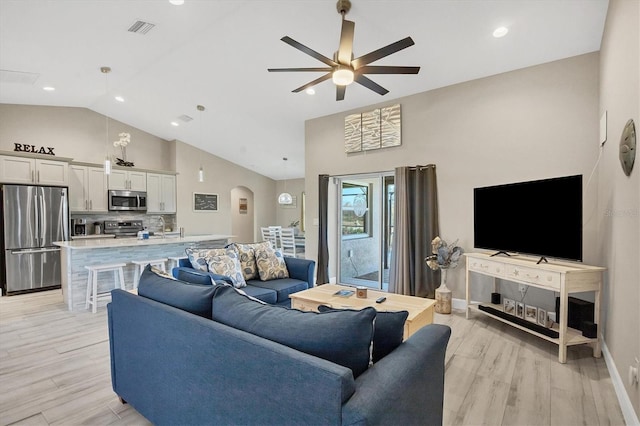 living room featuring light hardwood / wood-style floors, high vaulted ceiling, sink, and ceiling fan