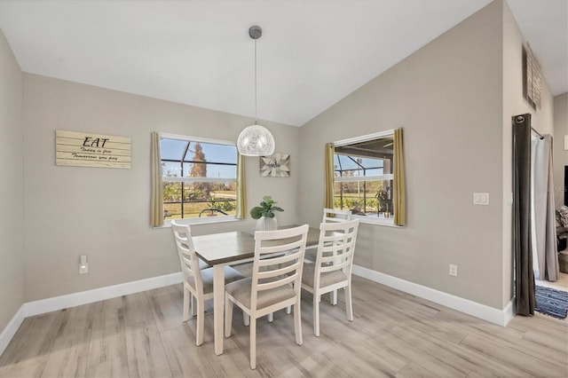 dining space with vaulted ceiling, light wood-type flooring, and plenty of natural light