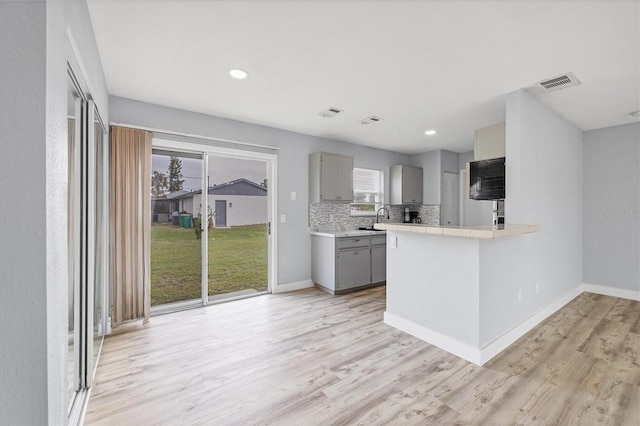 kitchen with light hardwood / wood-style floors, plenty of natural light, and gray cabinetry