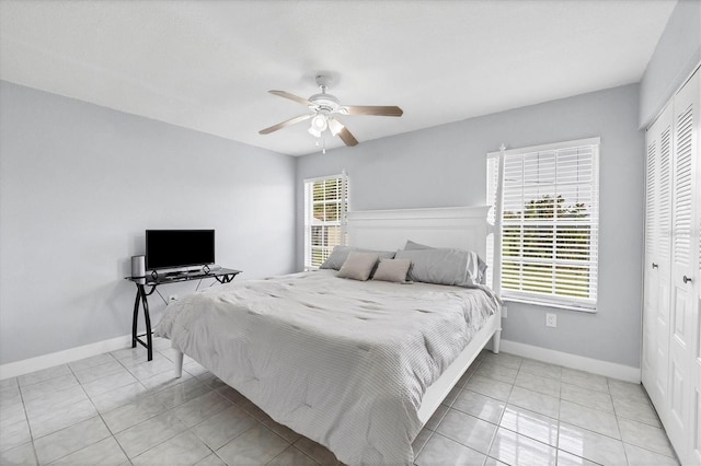 tiled bedroom with ceiling fan and a closet