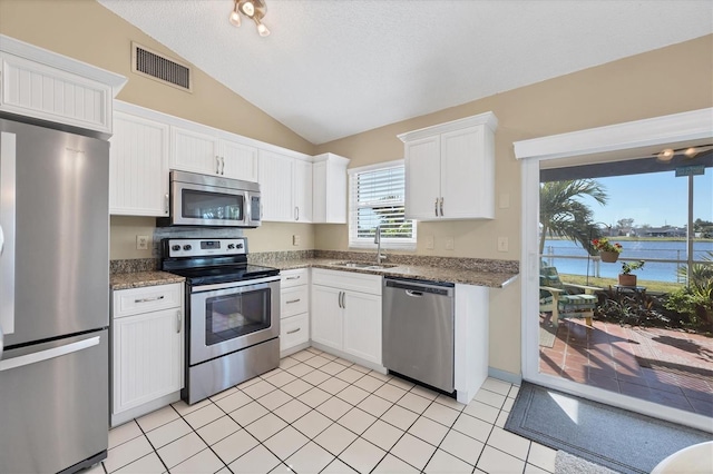 kitchen with a water view, sink, vaulted ceiling, white cabinetry, and stainless steel appliances