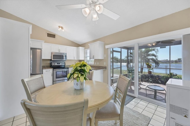 tiled dining room featuring a water view, ceiling fan, and lofted ceiling