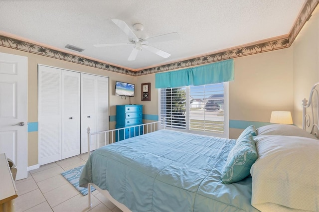 bedroom featuring ceiling fan, a closet, light tile patterned floors, and a textured ceiling