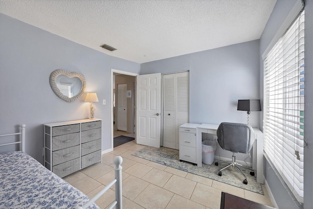 tiled bedroom with a textured ceiling and a closet