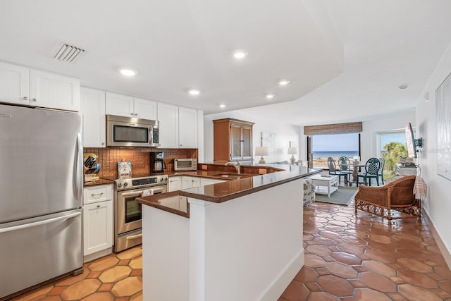 kitchen featuring white cabinetry, appliances with stainless steel finishes, backsplash, sink, and kitchen peninsula