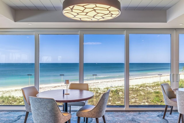 sunroom featuring a beach view and a water view