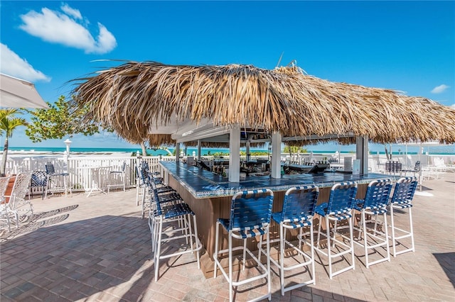 view of patio with an outdoor bar, a beach view, and a water view