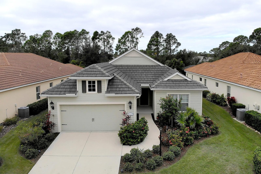 view of front of house with central air condition unit, a front yard, and a garage