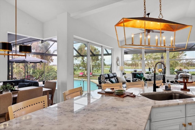 kitchen featuring white cabinetry, light stone countertops, pendant lighting, and a notable chandelier