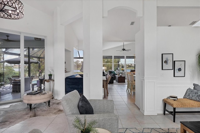 living room with high vaulted ceiling, ceiling fan with notable chandelier, and light tile patterned floors