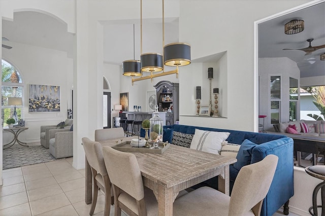 tiled dining space featuring a towering ceiling, plenty of natural light, and ceiling fan