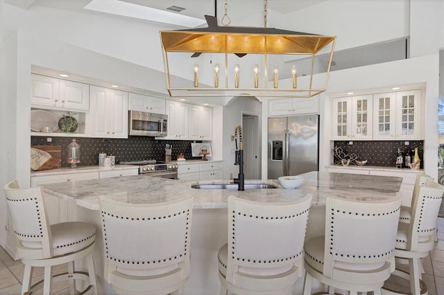 kitchen featuring light stone counters, hanging light fixtures, light tile patterned floors, appliances with stainless steel finishes, and white cabinets