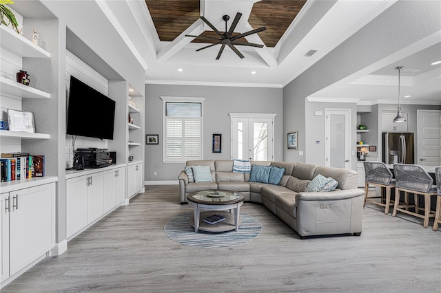 living room with ceiling fan, ornamental molding, a tray ceiling, and light wood-type flooring