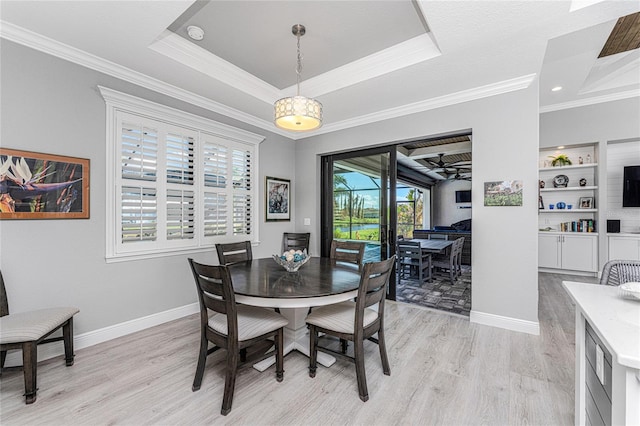 dining area featuring a raised ceiling, ceiling fan, light hardwood / wood-style flooring, ornamental molding, and built in features