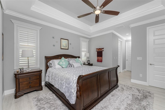 bedroom featuring ornamental molding, a tray ceiling, light hardwood / wood-style floors, and ceiling fan