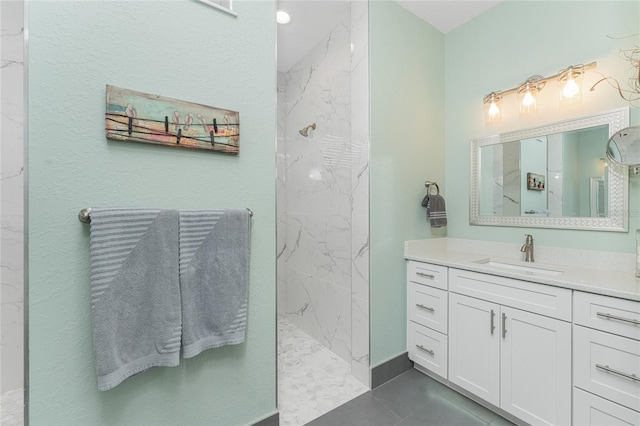 bathroom with vanity, a tile shower, and tile patterned flooring