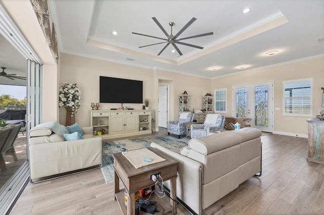 living room with a tray ceiling, ornamental molding, and light hardwood / wood-style flooring