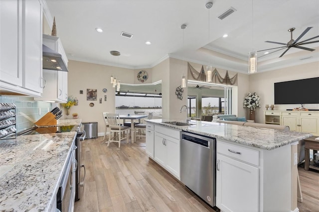 kitchen with a kitchen island with sink, sink, white cabinets, appliances with stainless steel finishes, and light hardwood / wood-style floors