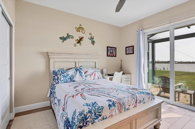 bedroom with a closet, access to exterior, a water view, and ceiling fan