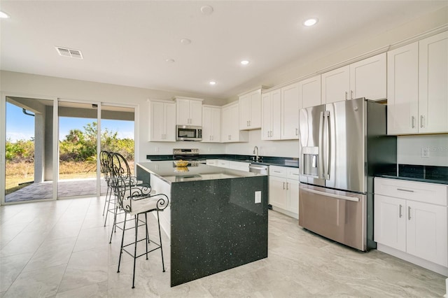 kitchen with white cabinetry, appliances with stainless steel finishes, sink, and a kitchen island