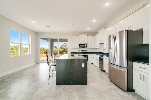 kitchen with a breakfast bar, white cabinetry, sink, a center island, and stainless steel appliances