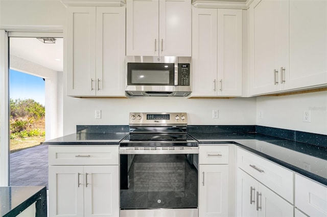 kitchen featuring white cabinetry, stainless steel appliances, and dark stone countertops