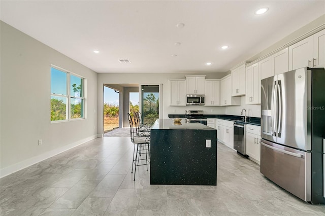 kitchen featuring sink, a breakfast bar, appliances with stainless steel finishes, a center island, and white cabinets