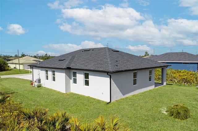 rear view of property with central AC unit and a lawn