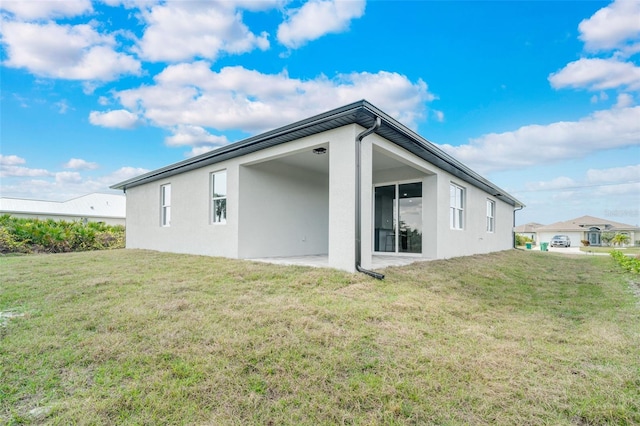 back of property with a yard and a patio