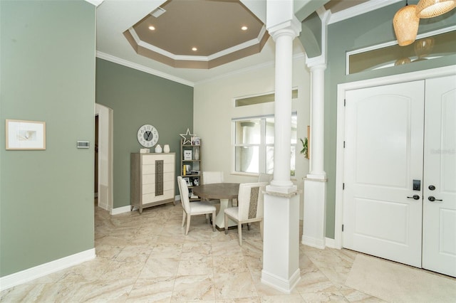 entryway featuring decorative columns, crown molding, and a raised ceiling