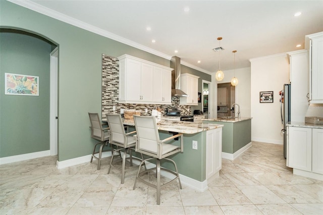 kitchen featuring hanging light fixtures, white cabinets, wall chimney exhaust hood, and appliances with stainless steel finishes