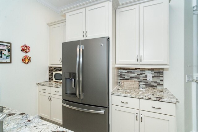 kitchen featuring white cabinetry, stainless steel fridge, and light stone countertops