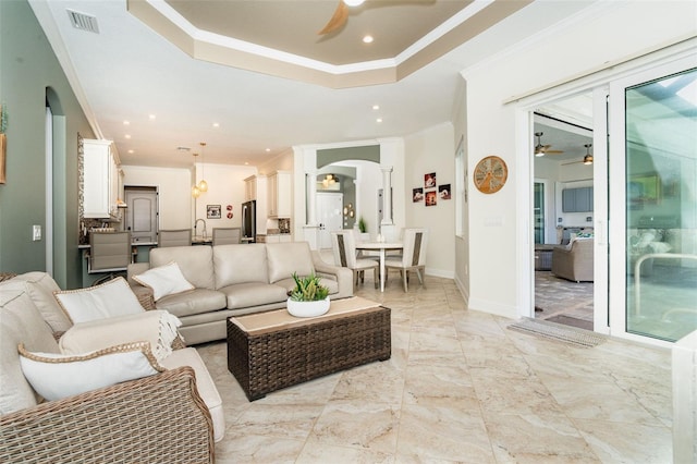 living room with crown molding, ceiling fan, and a tray ceiling