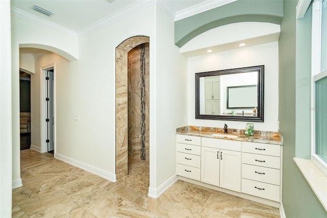 bathroom with a tile shower, vanity, and ornamental molding