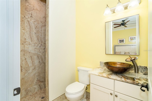 bathroom featuring vanity, tiled shower, ceiling fan, toilet, and crown molding