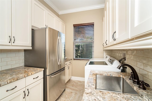 kitchen featuring light stone counters, crown molding, stainless steel refrigerator, and white cabinets