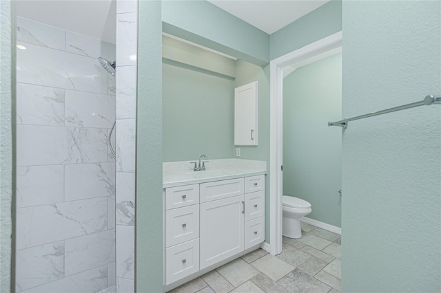 bathroom with tiled shower, vanity, and toilet