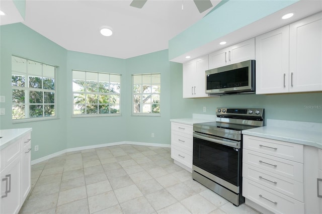 kitchen featuring ceiling fan, stainless steel appliances, white cabinets, lofted ceiling, and light tile patterned floors