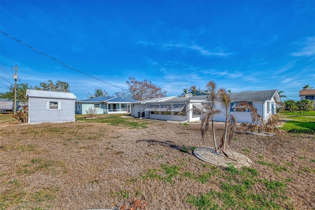 rear view of property featuring a lawn and a storage shed